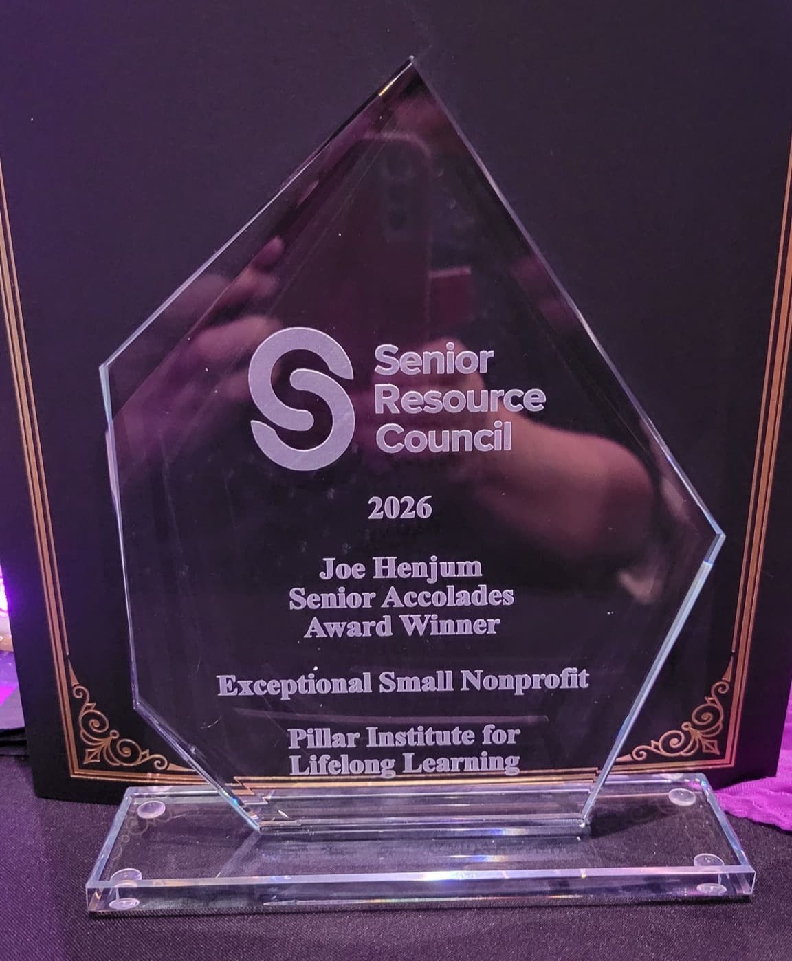 The glass Senior Accolades award engraved: 2026 Joe Henjum Senior Accolades Award Winner, Exceptional Small Nonprofit, Pillar Institute for Lifelong Learning